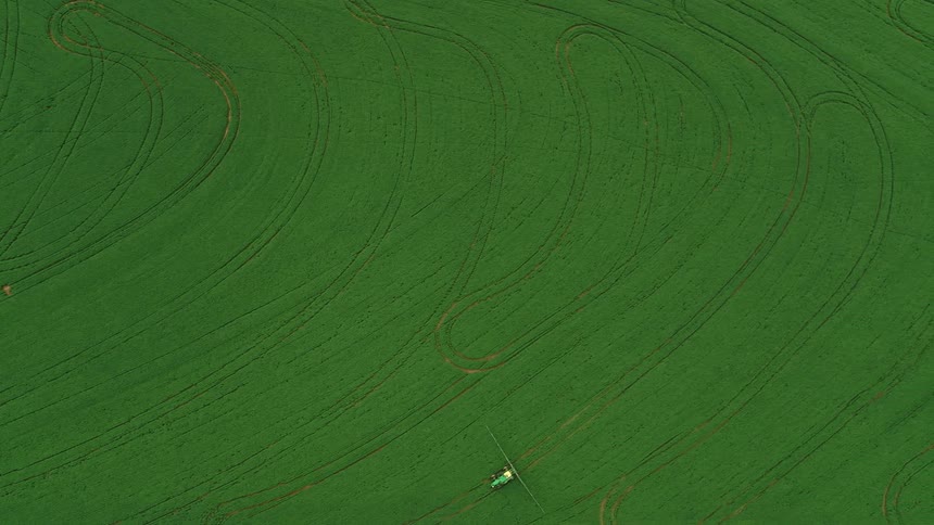 Vehicles move across grass leaving pattern created by their tracks