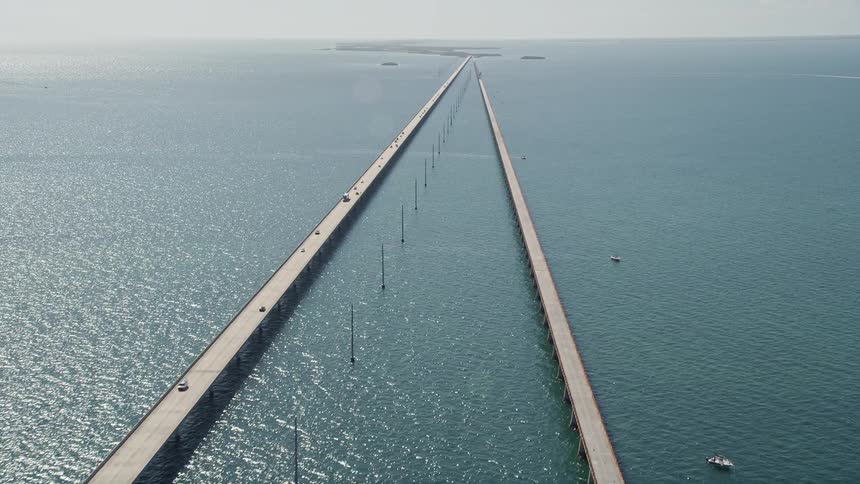 Aerial view of light traffic moving on Seven Mile Bridge in Florida as the sun shines over the Atlantic Ocean