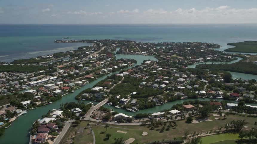 Aerial view of homes and canals in a sunny seaside neighborhood in Marathon Florida