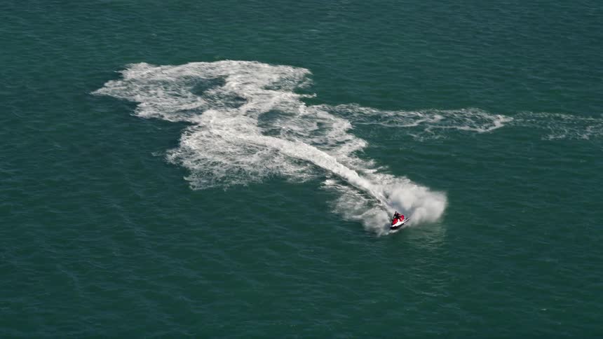 A jet skier speeds across the waves leaving a foaming wake while enjoying a sunny Florida day in Key West during summertime