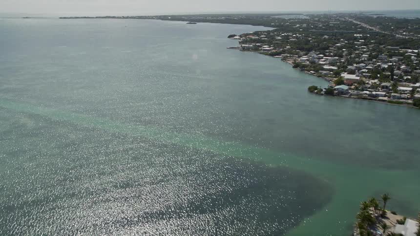 Aerial clip of coastal homes and shoreline along the Atlantic Ocean near Marathon Florida during a sunny summer day