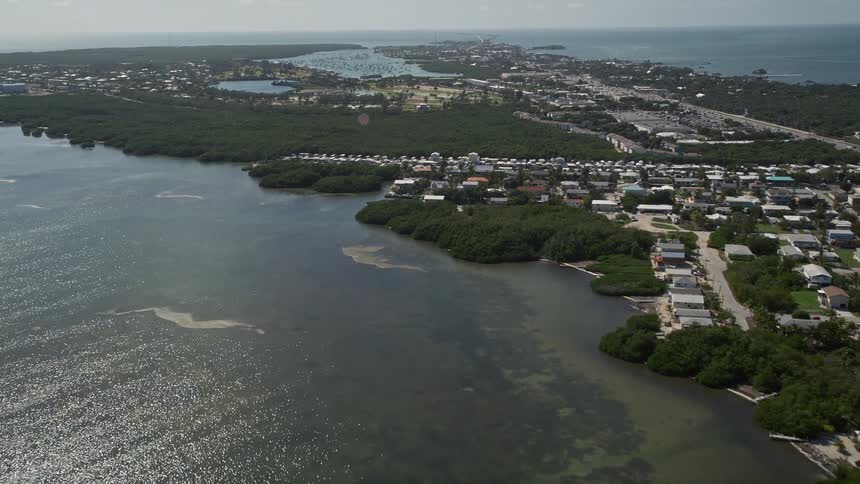 A stunning aerial view of Sombrero Country Club on the coast of Marathon FL showcasing a beautiful blue sky ocean shoreline and mangroves
