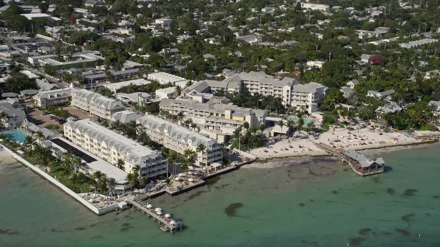 Aerial footage of The Reach - A Waldorf Astoria Resort on the shore of Key West Florida during the daytime showcasing its beautiful beaches and leisure activities