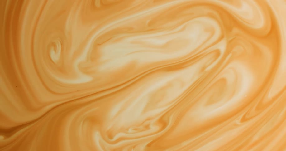 A swirling liquid of different shades of yellow and light brown gets an injection of more liquid
