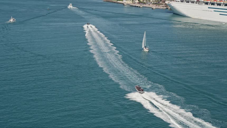 A speedboat races across the waves in Key West Florida and the camera tilts to reveal more boats enjoying the sunny day on the water