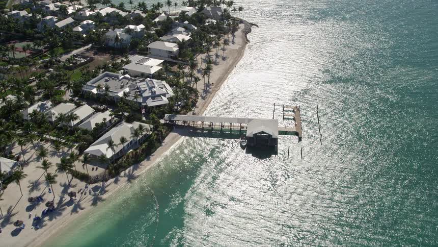 A ferry approaches a pier on Sunset Key in Key West Florida against a backdrop of houses along the coast