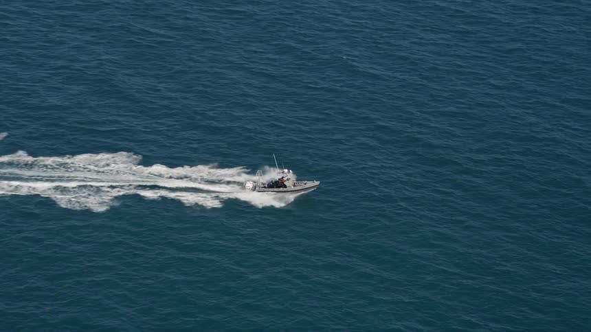 A fishing boat speeds through the sunny waters near the coast of Key West Florida in an aerial shot