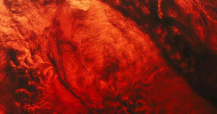 An illuminated cloud like substance erupts as it moves and spreads in a dark red environment