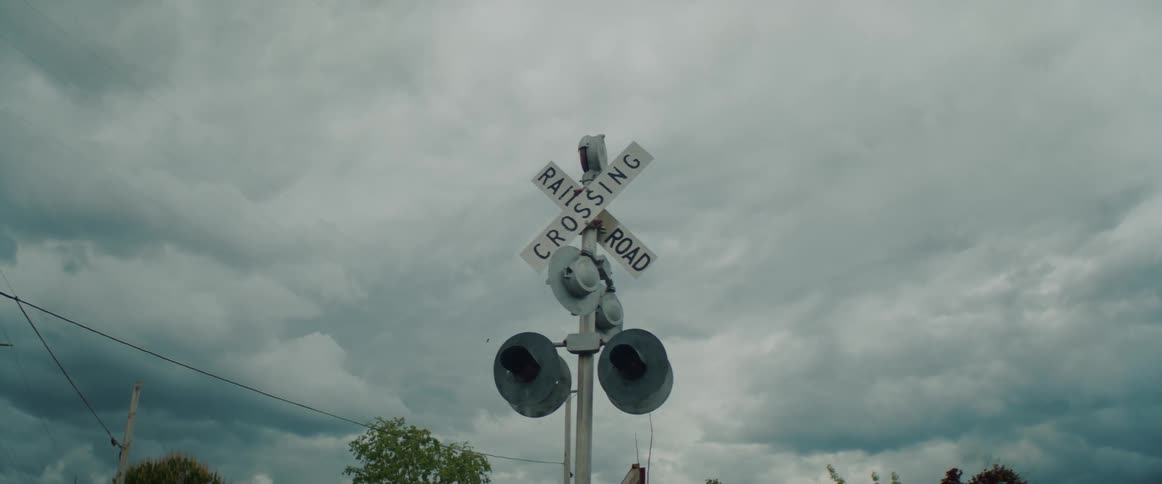 A railroad crossing sign under dark clouds