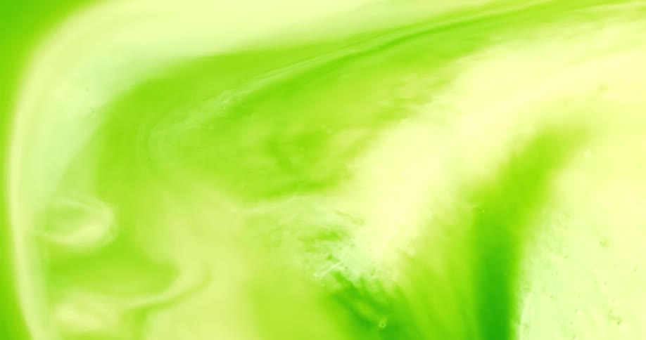 Green liquid being being around and swirled creating ripples on the surface