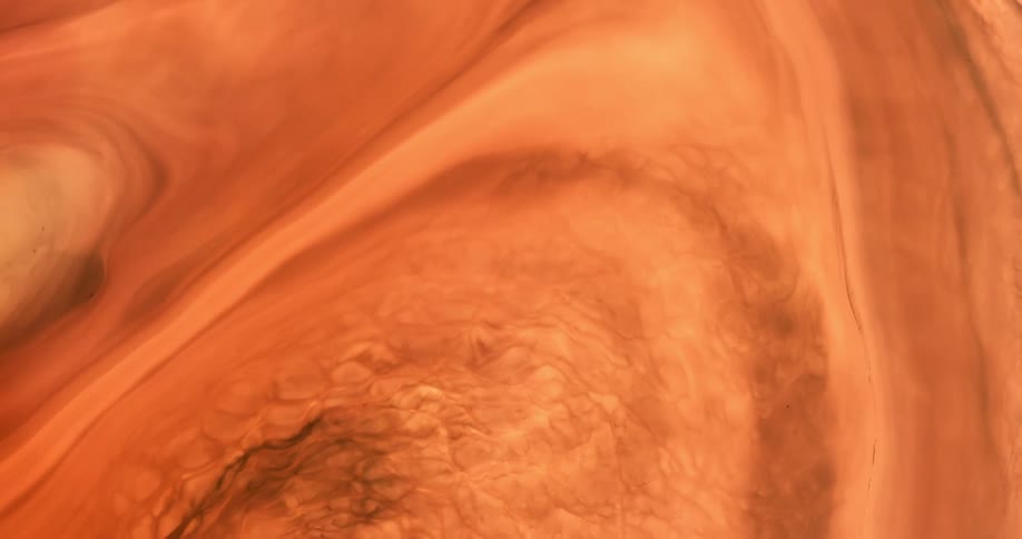 Dark swirls form in orange paint