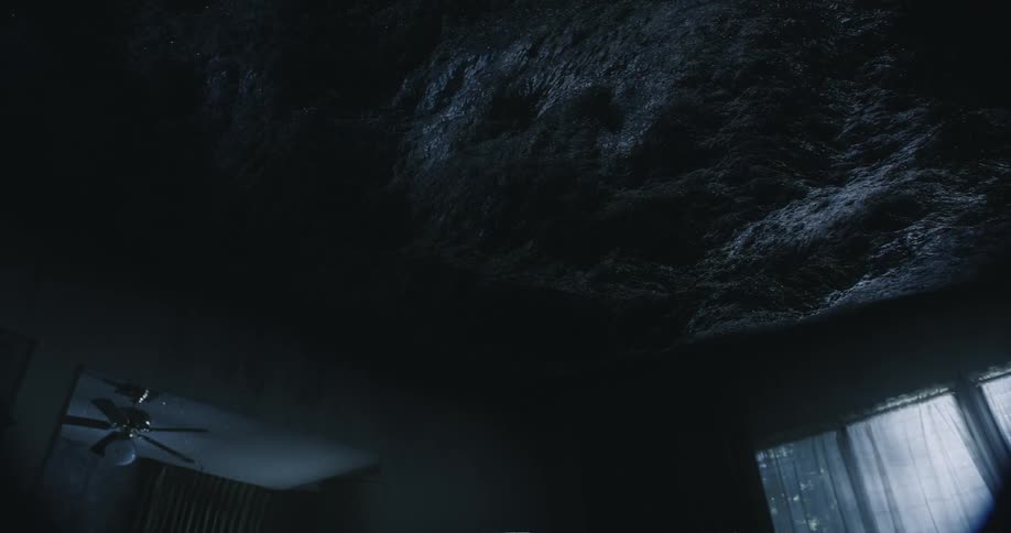 Waves ripple across the celiling of a dark and moody room with a ceilng fan and single window