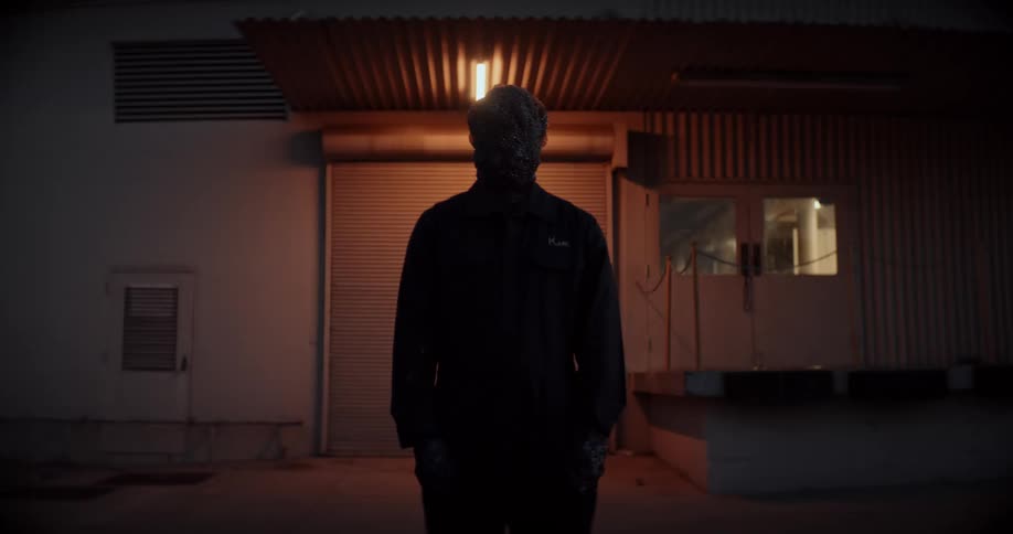 Man standing still and watching building is silhouetted against the light at night