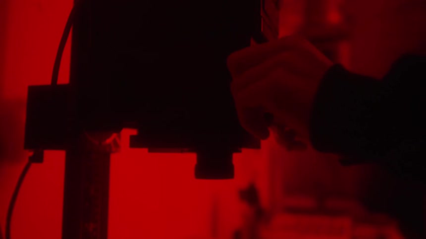 A person loads the camera in the dark room