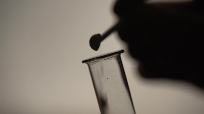 A person pours powder in the test tube
