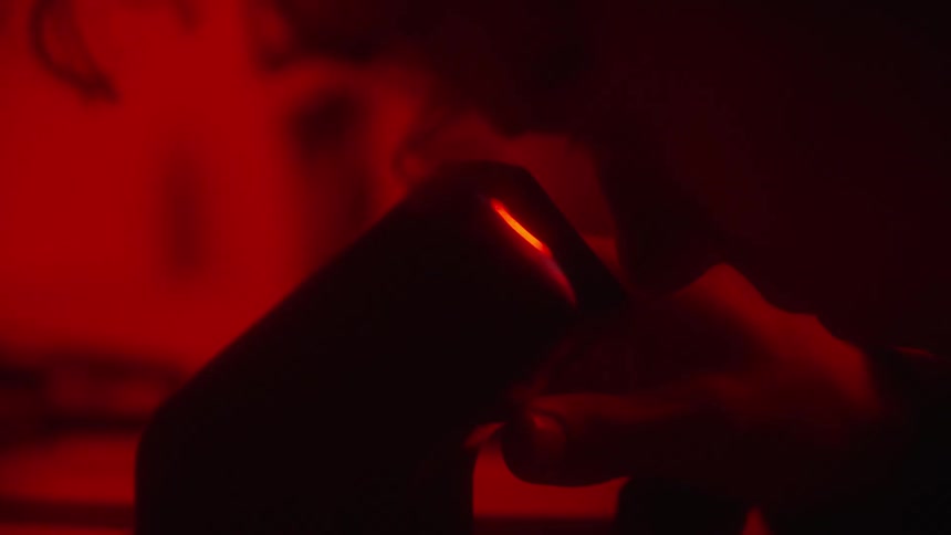 Photographer in dark room using a negative viewfinder to inspect negative film