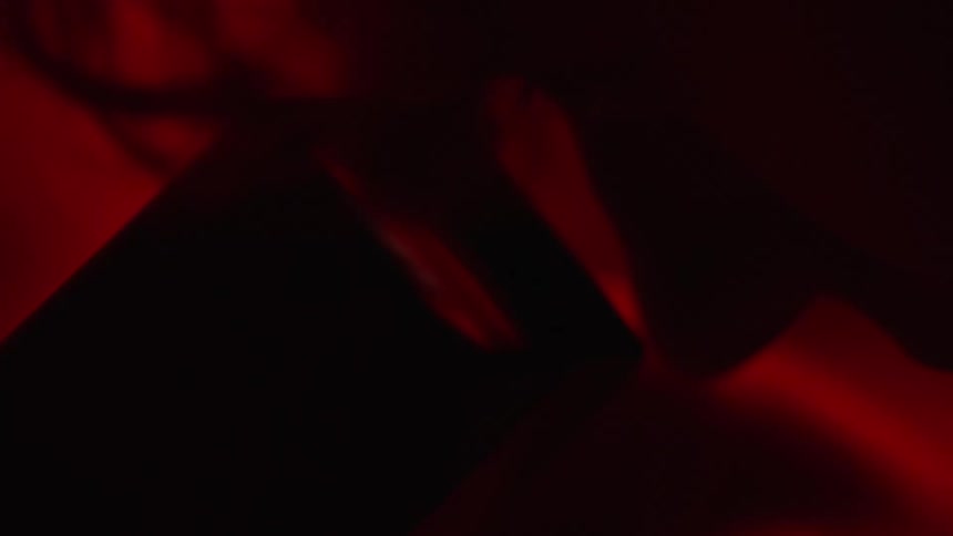 Photographer in dark room using a negative viewfinder to inspect negative filmf machine