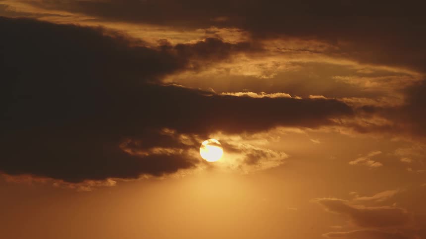 The sun shining can be seen from behind a dense and fluffy cloud