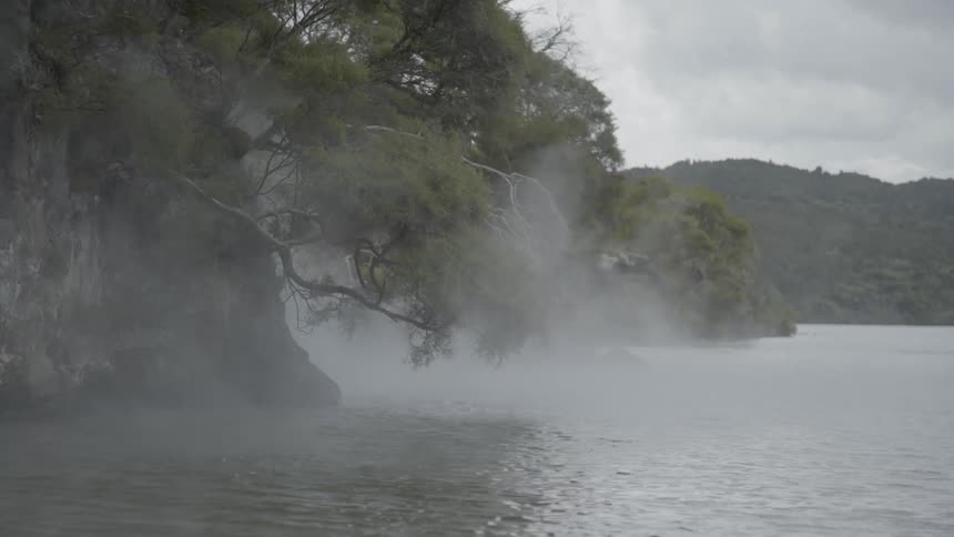 Steam rises from the water by the rocks