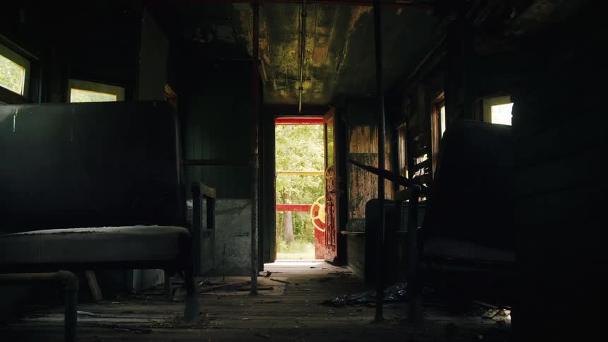 An interior view of an abandoned dwelling with old leather benches and a red door