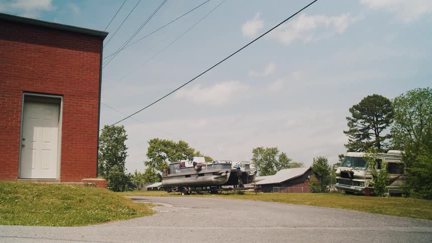 A suburban neighborhood with a pontoon boat and rv in the lawn