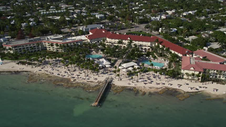 A stunning aerial view of the Casa Marina hotel and pier in Key West Florida with people enjoying the sunshine and beach activities