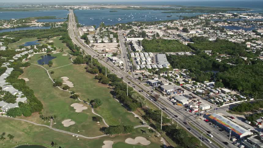 Following the Overseas Highway through Stock Island and Key West Florida - 5K aerial footage showcasing the beautiful coastline shoreline and transportation infrastructure