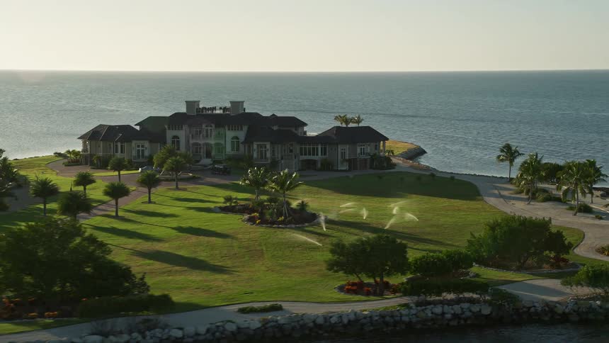 An aerial view of a rustic mansion with a large garden surrounded by water in Marathon Florida at dusk