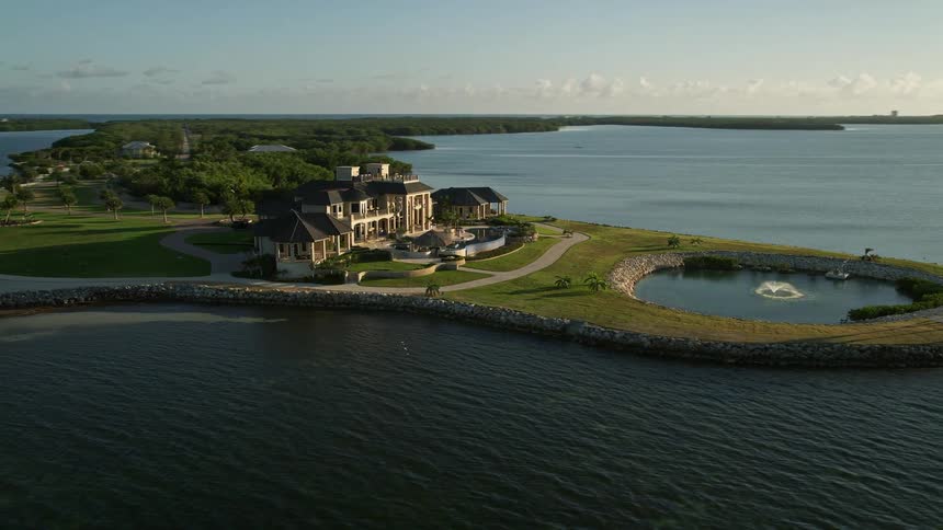 Aerial footage of a mansion on the Florida shore with rustic and upscale homes at dusk showcasing the isolated houses on different keys