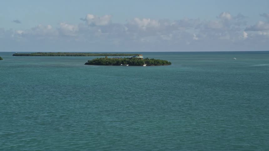 Aerial footage of a rustic home on a small Florida island surrounded by shoreline beachfront and coastline offering stunning views of the Atlantic Ocean