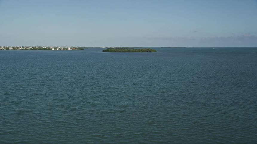 A low flying aerial view towards mangroves and shoreline in Cudjoe Bay Florida with sunny weather