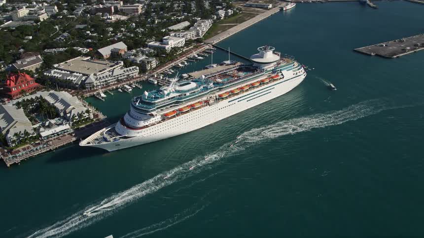 An aerial view of a Royal Caribbean cruise ship docked in Key West Florida with boats and jet skis moving around and people enjoying the sunny day