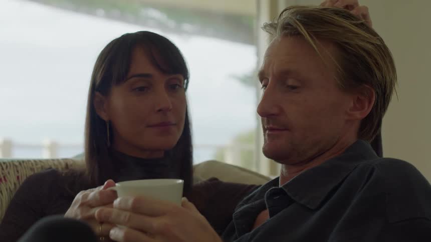 Man and woman sitting on the couch intimate conversation coffee smiling touching daytime