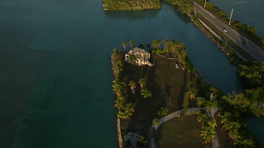 Approaching an isolated house on a rustic island property tilting down to a birds eye view at sunset over Craig Key Florida