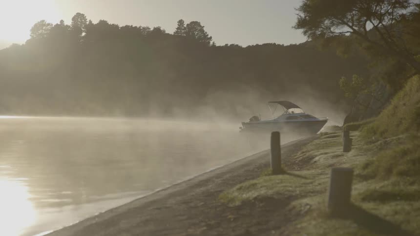 A boat is docked near the shore at sunset