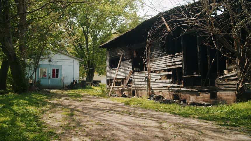 A smaller building is located next to one that is falling apart