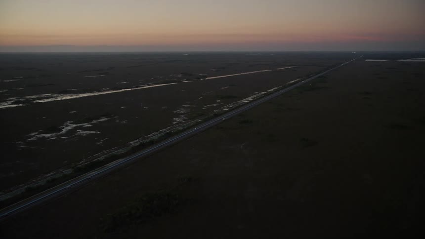 Aerial footage of driving on South Dixie Highway during twilight over wetlands in Southern Glades Florida