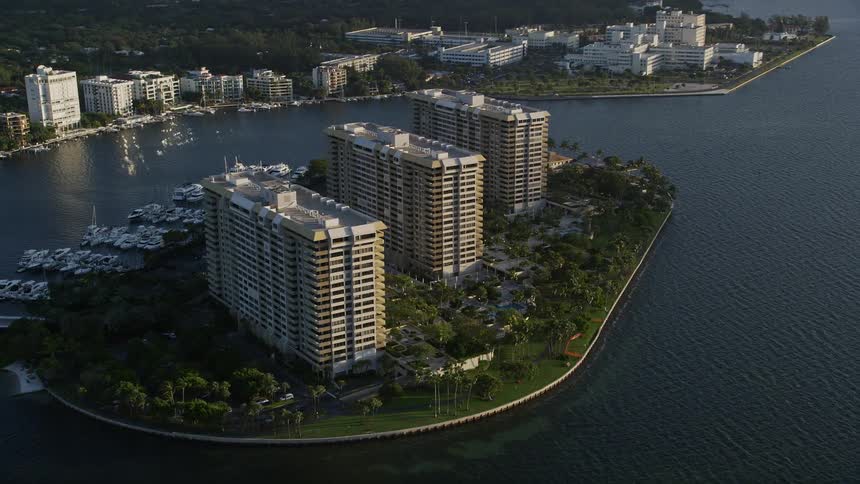 An aerial view of condominium complexes on Grove Isle Florida during sunrise showcasing waterfront property and metropolitan areas