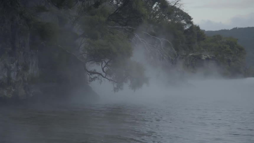 Steam rises from the water near the rocks