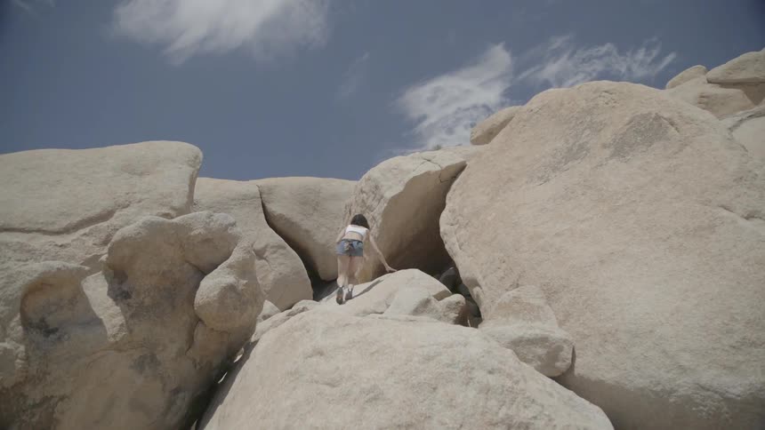 A woman is climbing over huge boulders