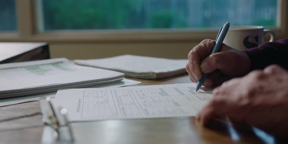 A man is writing at his desk