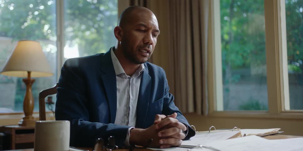 A man sits in his office and speaks as he looks across his desk