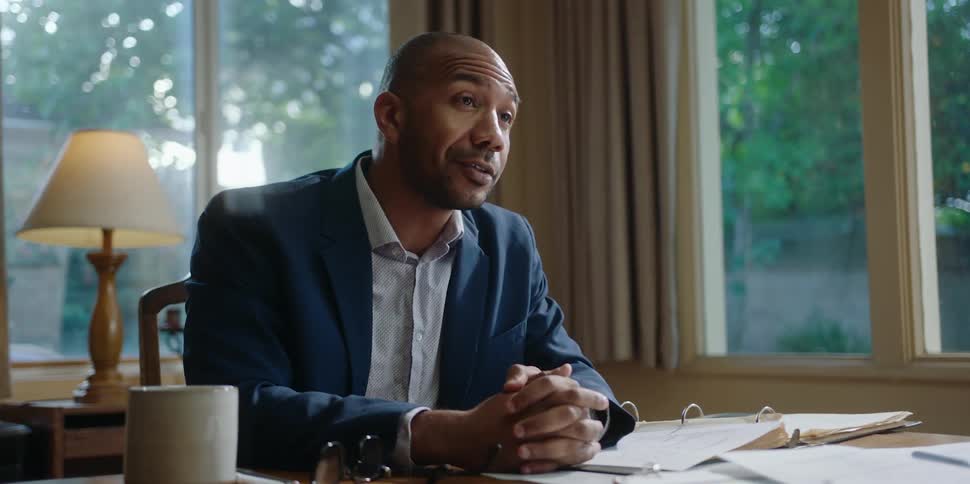 A man chats with a client at his desk in a home office
