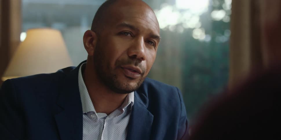 A business man sits in his office and talks with another person