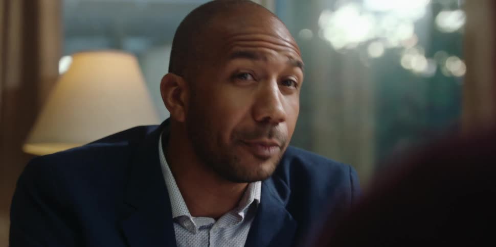 A man speaks to someone while sitting behind his desk