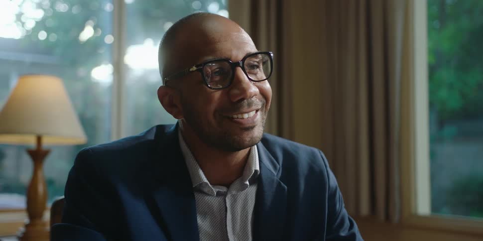 A black man talks to someone nodding and smiling