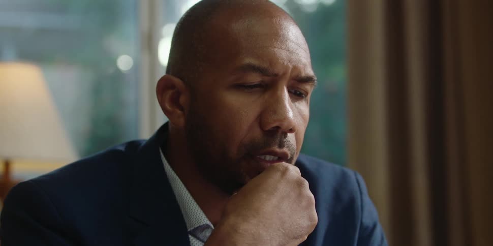 A man rests his chin on his hand while speaking