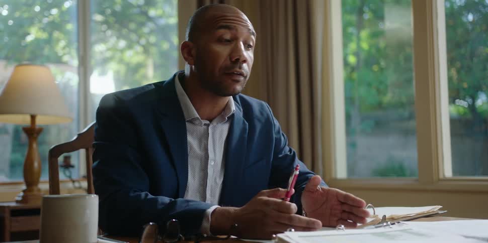 A man talks to someone in front of him moving his hands while holding a pen