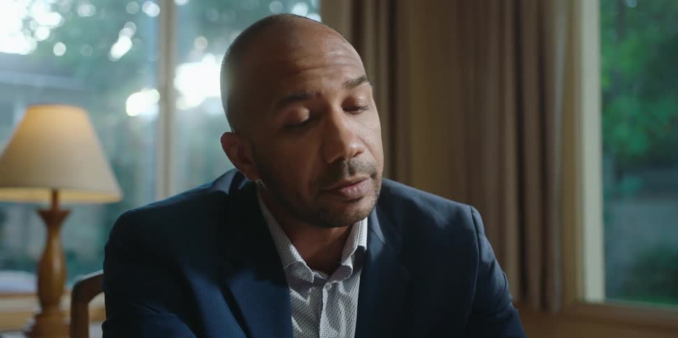 A man is sitting down and wearing a suit indoors