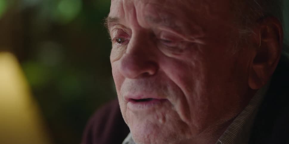 An old man wipes his tears off his face as he talks